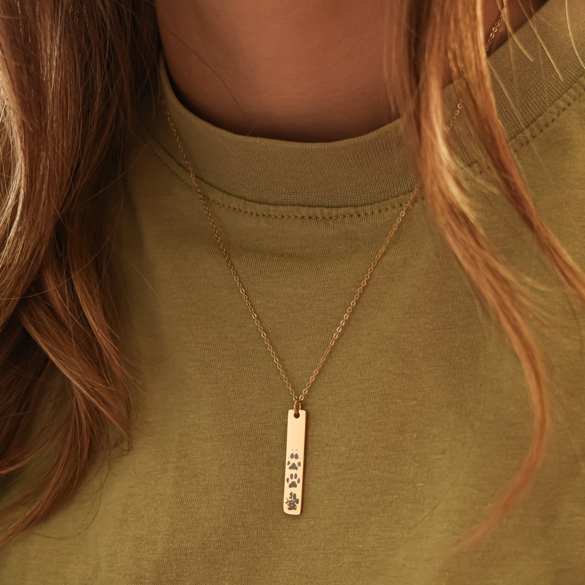 Ketting met verticaal bar hangertje gegraveerd met meerdere pootafdrukken goud stainless steel