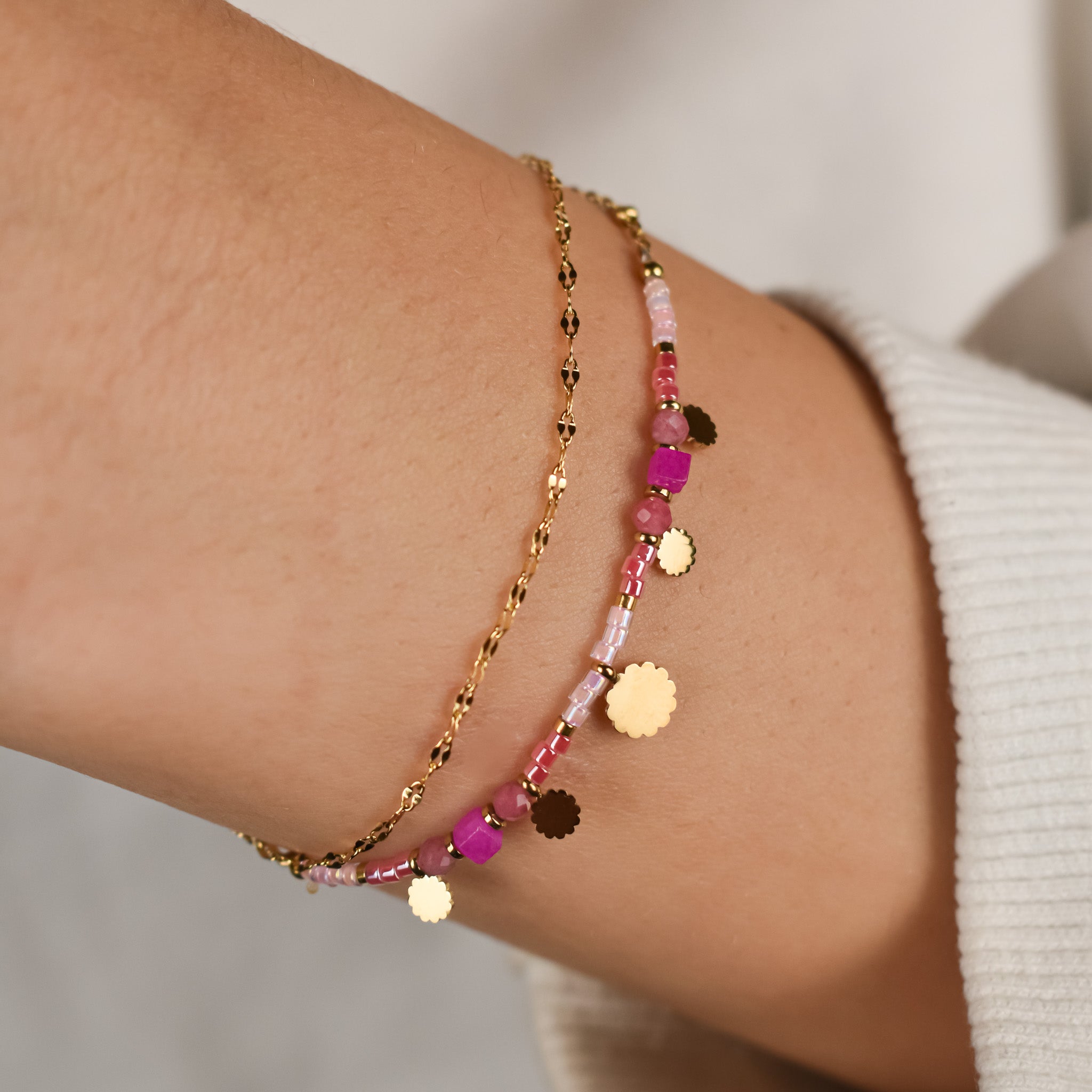 Goudkleurige dubbele armband met schakelarmband en een armband met roze kralen en ronde bedels.